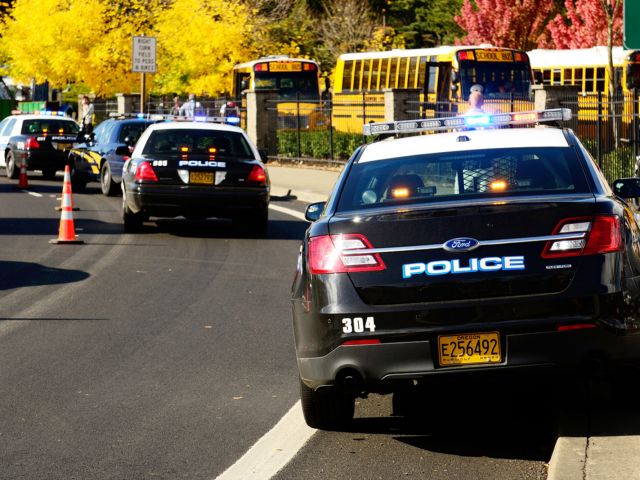 Police cars and school buses at the site of an accident. The school will need to send out a crisis communication.