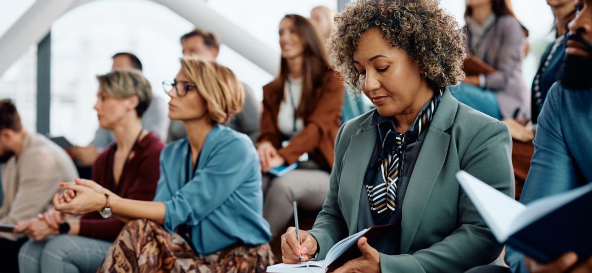 Woman writes in her notebook at a conference