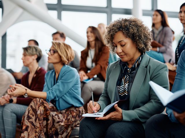 Woman writes in her notebook at a conference